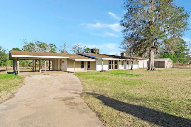 single story home with covered porch, an outdoor structure, a front lawn, and a carport