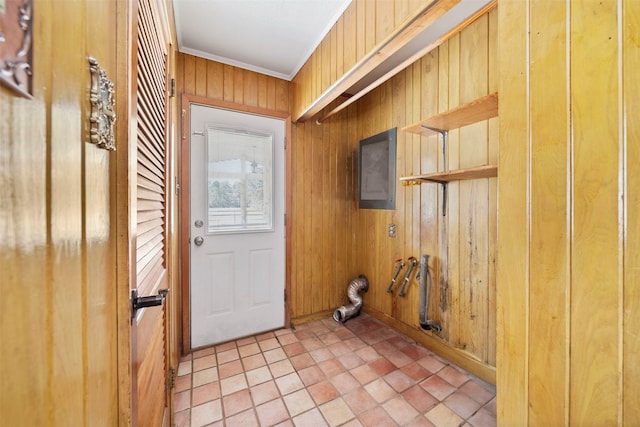 entryway with tile patterned floors, wooden walls, electric panel, and crown molding