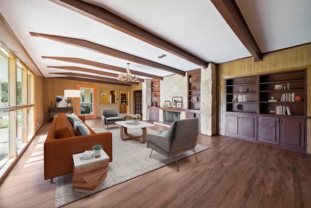 living room with a notable chandelier, hardwood / wood-style flooring, wooden walls, and a fireplace