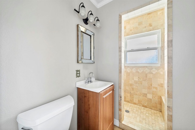 bathroom with vanity, crown molding, tiled shower, and toilet