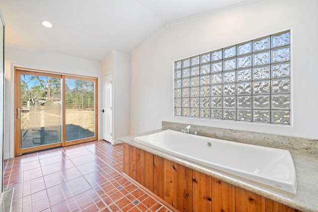 bathroom featuring lofted ceiling, ornamental molding, a bathtub, and tile patterned flooring