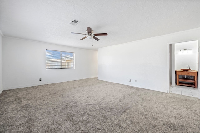 unfurnished living room featuring ceiling fan, a textured ceiling, ornamental molding, and light colored carpet