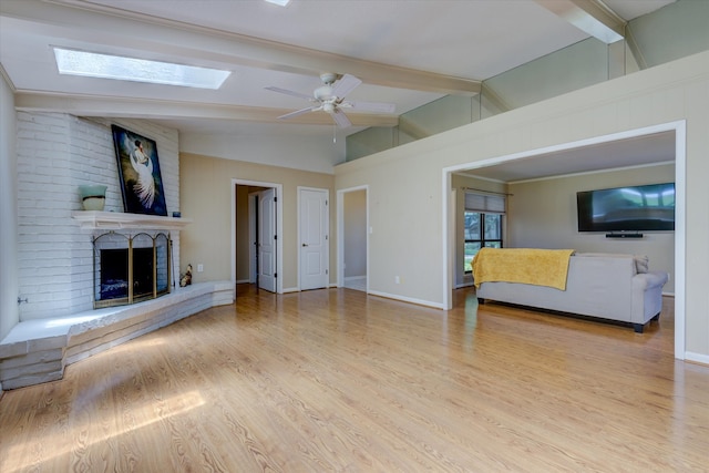 unfurnished living room with vaulted ceiling with skylight, a fireplace, light wood-type flooring, and ceiling fan