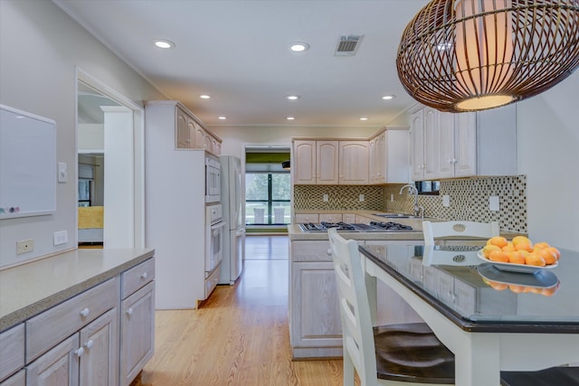 kitchen featuring backsplash, light brown cabinetry, light hardwood / wood-style floors, sink, and white appliances