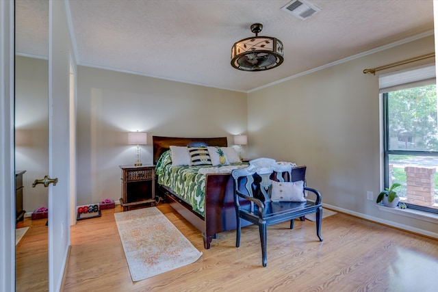 bedroom featuring light hardwood / wood-style floors, ornamental molding, and multiple windows