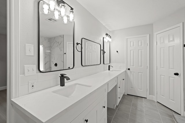 bathroom featuring vanity, tiled shower, and tile patterned flooring