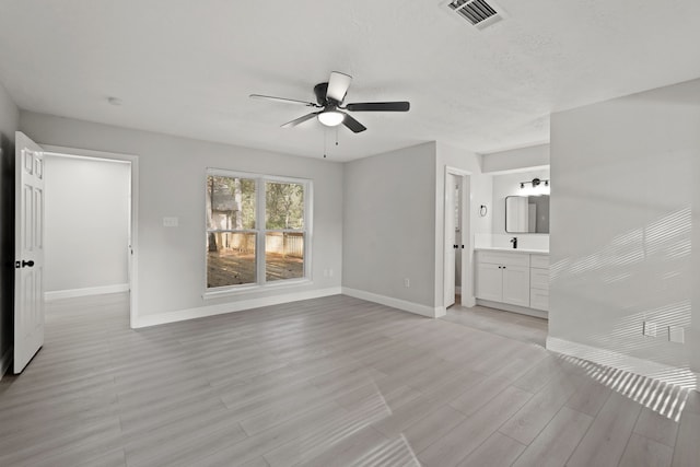 empty room with sink, ceiling fan, and light hardwood / wood-style flooring