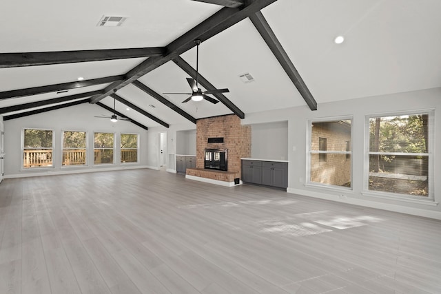 unfurnished living room with ceiling fan, lofted ceiling with beams, light hardwood / wood-style flooring, and a brick fireplace