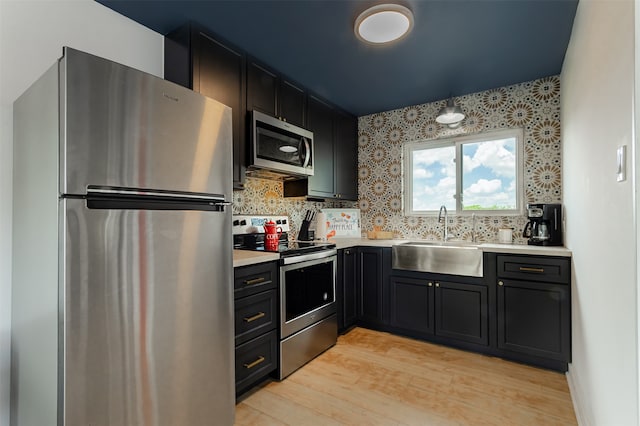 kitchen with stainless steel appliances, sink, light wood-type flooring, and tasteful backsplash