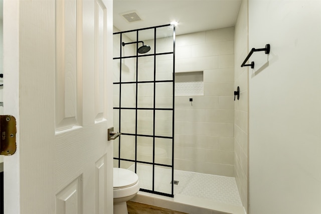 bathroom featuring hardwood / wood-style floors, toilet, and tiled shower