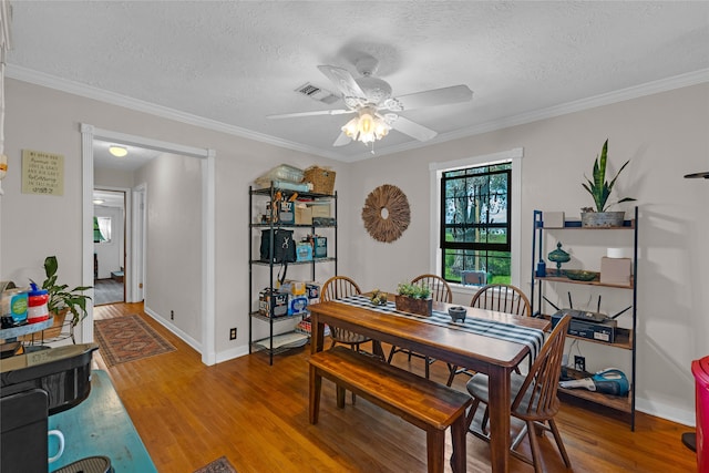 dining space with hardwood / wood-style floors, crown molding, a textured ceiling, and ceiling fan