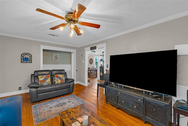 living room featuring a textured ceiling, crown molding, wood-type flooring, and ceiling fan