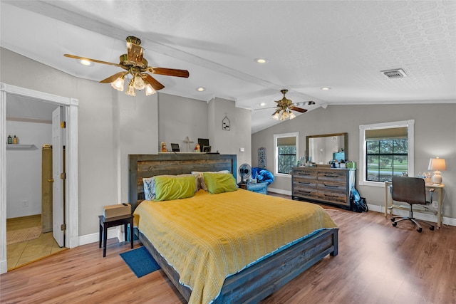 bedroom with hardwood / wood-style floors, a textured ceiling, vaulted ceiling, and ceiling fan