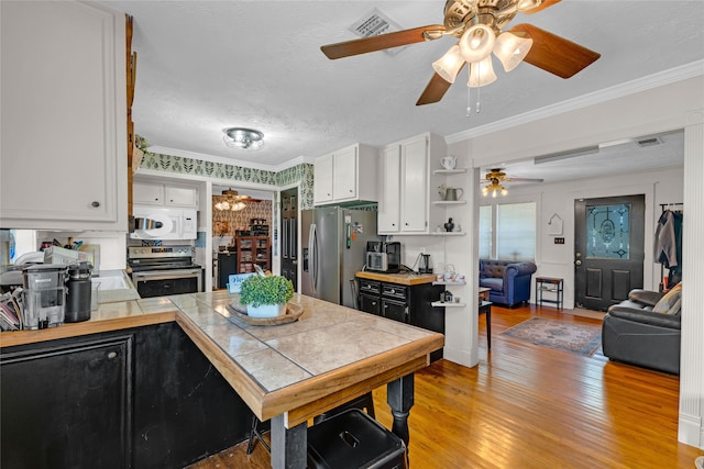 kitchen with white cabinets, appliances with stainless steel finishes, a textured ceiling, crown molding, and tile counters