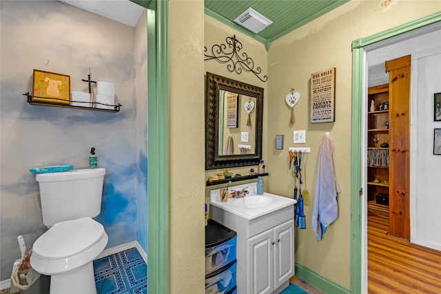 bathroom with vanity, toilet, ornamental molding, and hardwood / wood-style floors