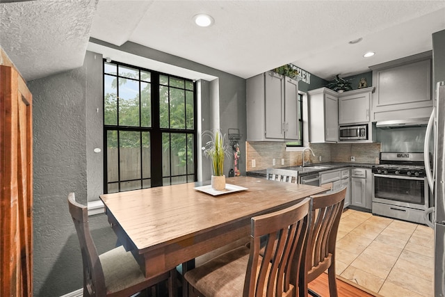 kitchen featuring gray cabinetry, stainless steel appliances, decorative backsplash, and a textured ceiling