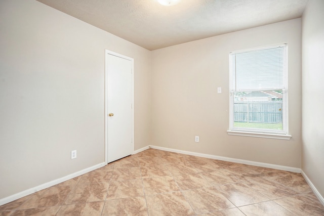 spare room with a textured ceiling and light tile patterned flooring