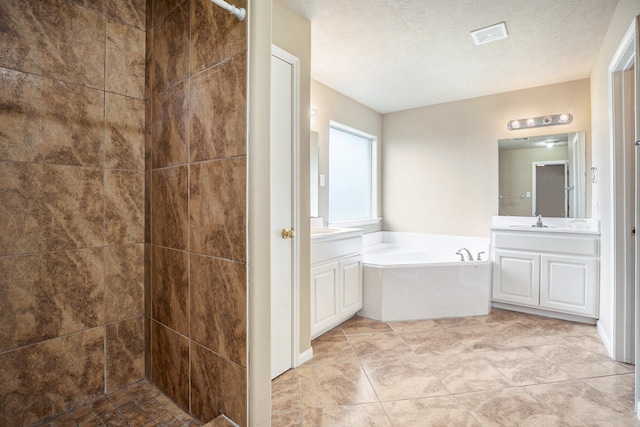 full bathroom with visible vents, a garden tub, two vanities, tiled shower, and a textured ceiling