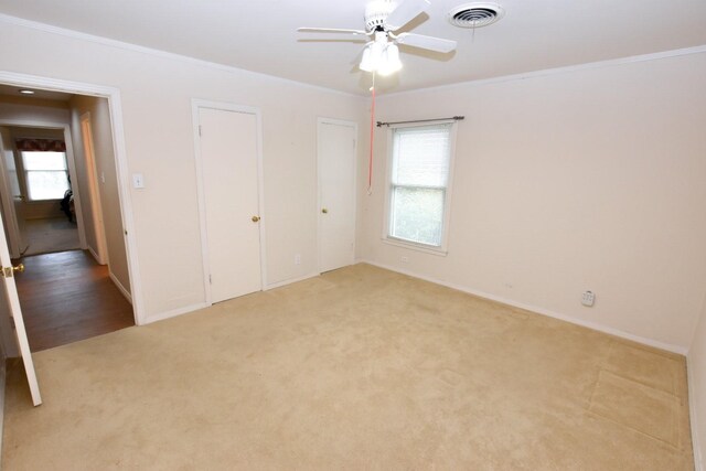 unfurnished bedroom featuring light carpet, crown molding, and ceiling fan