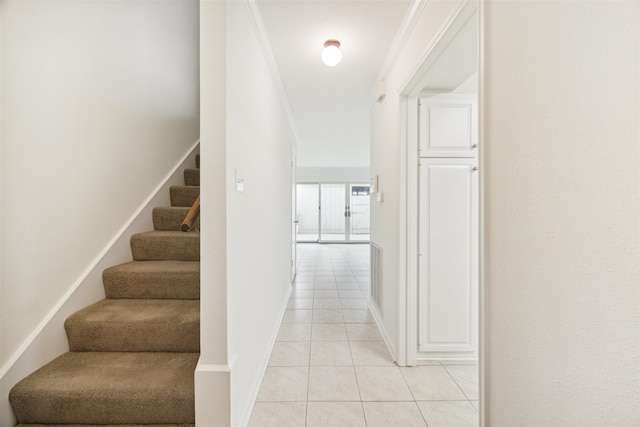 hallway featuring ornamental molding and light tile patterned floors