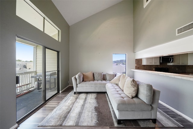 living room featuring dark hardwood / wood-style floors, high vaulted ceiling, and a healthy amount of sunlight