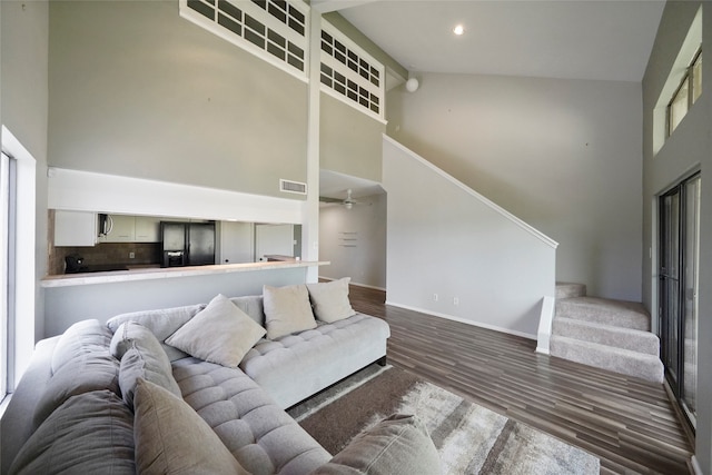 living room with ceiling fan, dark hardwood / wood-style flooring, and high vaulted ceiling