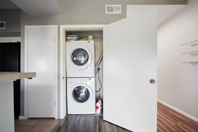 laundry room featuring dark hardwood / wood-style flooring and stacked washer and dryer