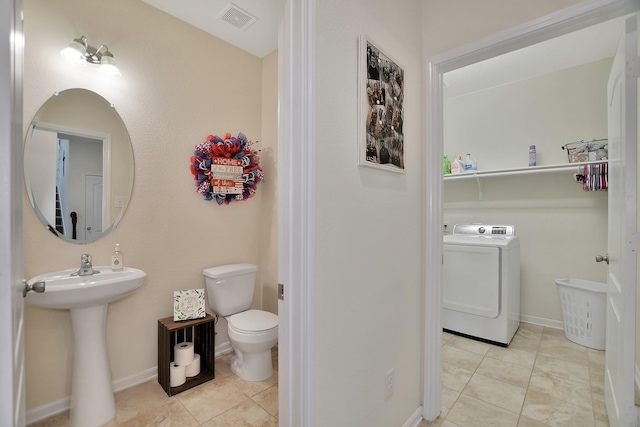 bathroom featuring tile patterned floors, toilet, and washer / clothes dryer