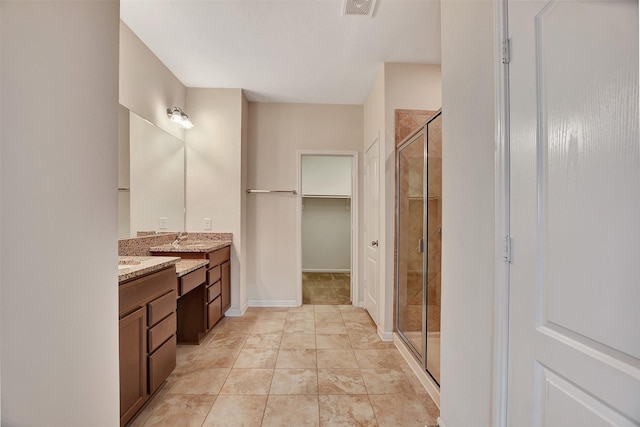 bathroom featuring a shower with shower door and sink