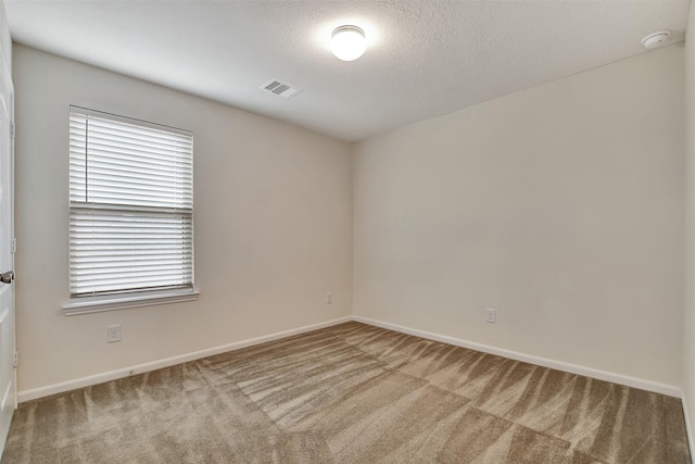 spare room with light carpet and a textured ceiling