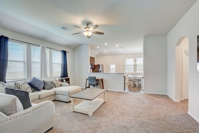 carpeted living room with ceiling fan with notable chandelier