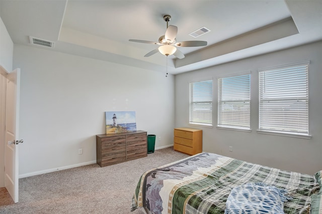 bedroom featuring ceiling fan, light carpet, and a tray ceiling