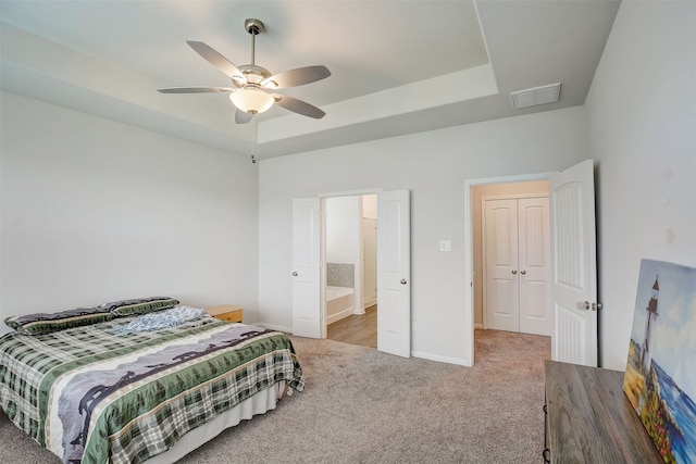 carpeted bedroom with connected bathroom, a raised ceiling, and ceiling fan