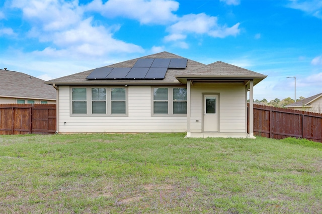 back of house with a yard and solar panels