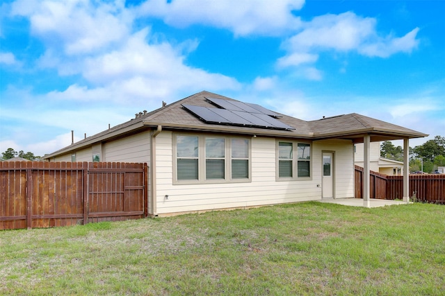 back of property featuring a patio area, solar panels, and a lawn