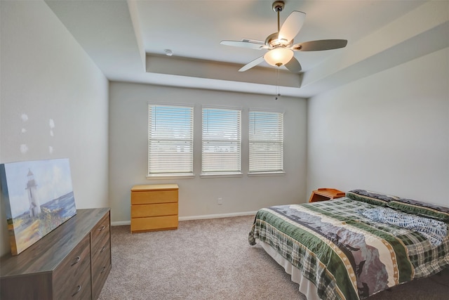 carpeted bedroom featuring ceiling fan and a tray ceiling