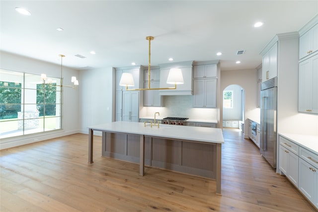 kitchen with light hardwood / wood-style flooring, plenty of natural light, decorative light fixtures, and built in refrigerator