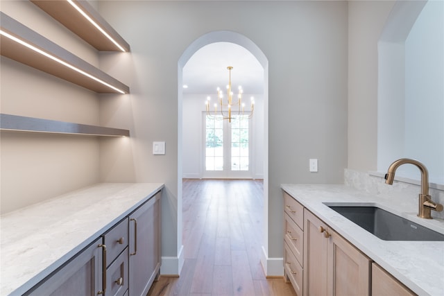 kitchen featuring a chandelier, sink, light stone counters, and light hardwood / wood-style floors