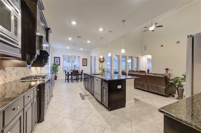 kitchen featuring stainless steel appliances, dark stone countertops, backsplash, a kitchen island with sink, and pendant lighting