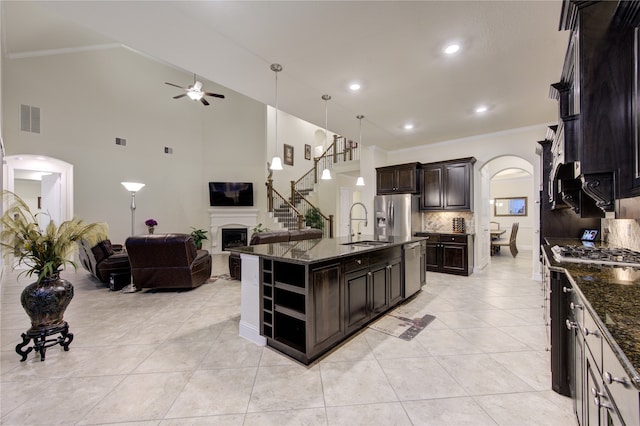 kitchen featuring a center island with sink, dark brown cabinetry, sink, backsplash, and appliances with stainless steel finishes