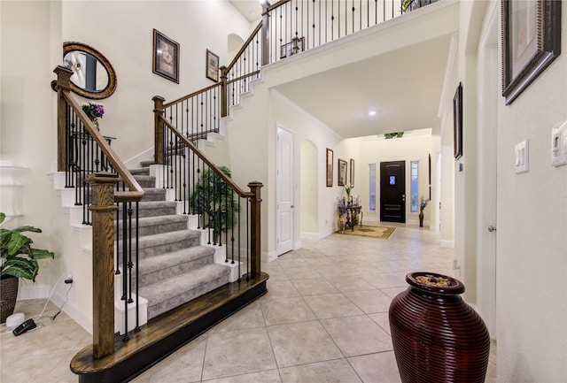 tiled entryway with crown molding and a towering ceiling