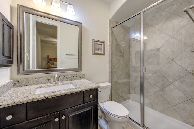 bathroom featuring toilet, vanity, and a shower with shower door