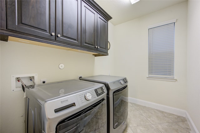 laundry area with cabinets, washing machine and dryer, and light tile patterned floors