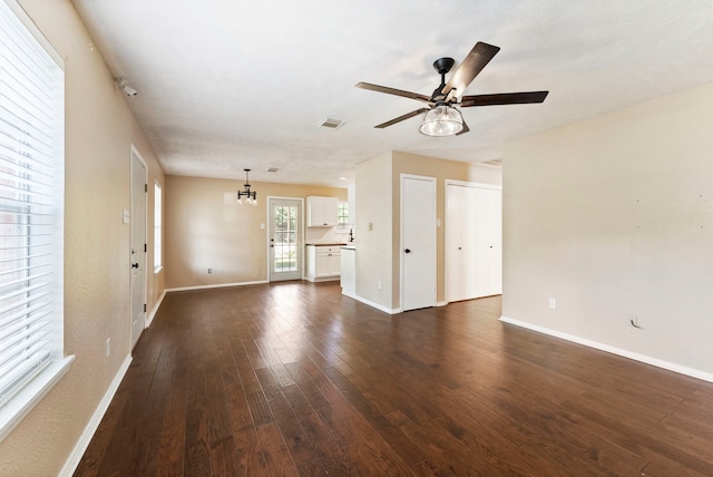 unfurnished living room featuring dark wood-type flooring and ceiling fan with notable chandelier