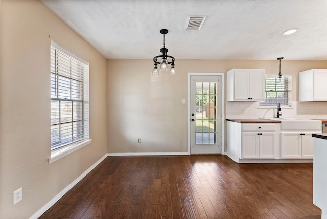 kitchen with decorative backsplash, white cabinets, hanging light fixtures, and dark hardwood / wood-style flooring