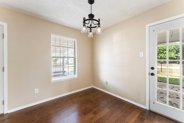 unfurnished dining area featuring a chandelier and dark hardwood / wood-style floors