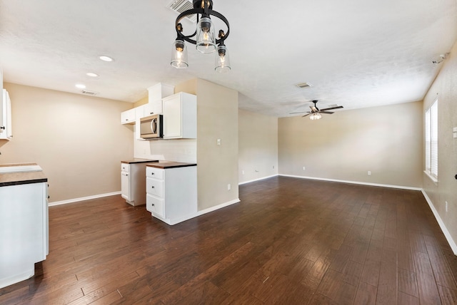 kitchen featuring dark hardwood / wood-style floors, backsplash, sink, white cabinetry, and ceiling fan with notable chandelier