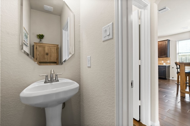 bathroom featuring hardwood / wood-style floors, sink, and tasteful backsplash