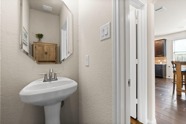 bathroom featuring hardwood / wood-style flooring, tasteful backsplash, and sink