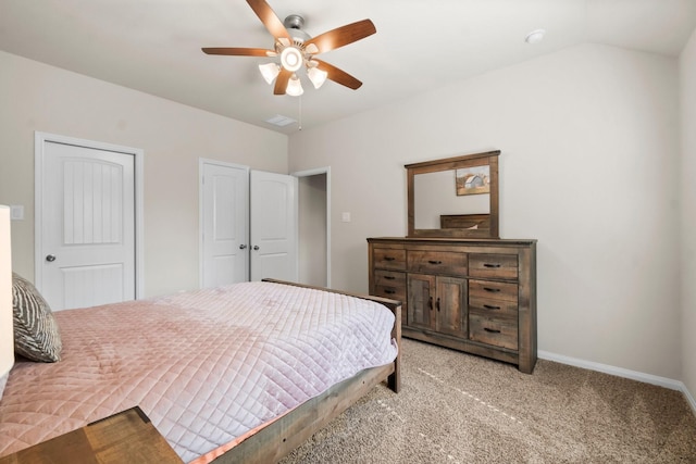 carpeted bedroom featuring ceiling fan, lofted ceiling, and two closets